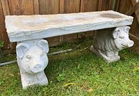 Full view of grey resin garden bench showing pig-legged ends and leafy vine design along seat edges.
