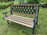 Front and side angled view showing oak wood slats and cast iron frame with decorative lattice backrest.