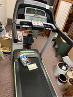 Front view of treadmill showing belt, accessories including maintenance kit and owner's manual on the belt.