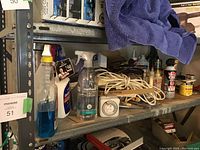 Shelf with various household cleaning sprays and maintenance tools including method brand products, extension cords, and timers.