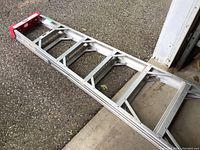 Full length view of the 6-step aluminum ladder laid on driveway and adjacent to garage door.