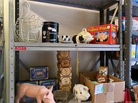 Full view of metal shelving unit displaying pig collectibles including piggy banks, tins, wooden blocks, plush toys, and bacon press