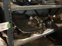 Shelf with stacked silverplate trays, candlesticks, and a pitcher showing tarnish and need for cleaning.