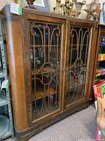 Full front view of cabinet showing double glass doors with fretwork and curved side edges