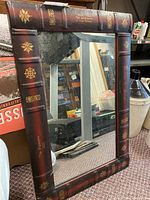 Full view of the rectangular wall mirror with the book spine themed frame showing titles and decoration.