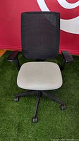 Front view of a Steelcase Reply chair showing black mesh backrest and light alpine fabric seat cushion on green floor.