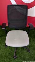 Front view of the Steelcase Reply chair showing black mesh back and light fabric seat with minor stains, armrests, wheels, and chair base.