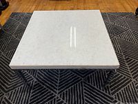 Top view of square grey marble coffee table showing smooth surface with subtle crystallization and reflection of light.
