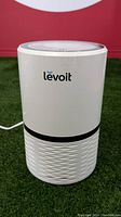 Front view of LEVOIT air purifier showing brand name and cylindrical white body with vented lower section.