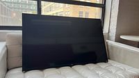 Front view of TV leaning on couch showing screen and bezel