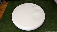 Top view of round white coffee table showing three recessed circular indents of different sizes on glossy surface.