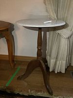 Full view of the pedestal accent table showing its round white marble top and wooden tripod base with claw feet.