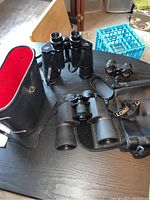 All three sets of binoculars displayed together with cases on a black table.