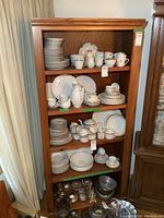 Front view of the oak bookshelf filled with assorted dishes demonstrating size and shelves.