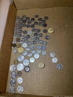 Wide view of multiple coins arranged on a cardboard surface showing variety in size and design