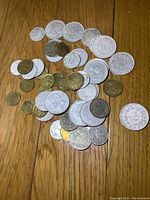 Photo of assorted old French coins displayed on wood surface showing different sizes and materials