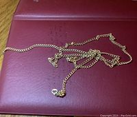 Full view of tangled gold chain on red surface