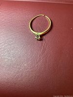 Ring laid flat showing the gold band and floral prong setting with central stone.