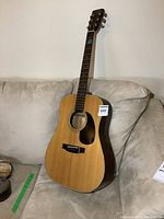 Full front view of the Sigma Guitars DM-3 acoustic guitar resting on sofa