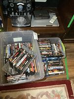 Karaoke machine on shelf with DVD player and remote on top, four bins filled with DVDs and Blu-rays below.