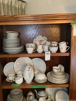 Two wooden shelves filled with china tea and dinnerware sets