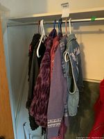 Photo of hanging clothing including denim vest and various sweaters/vests.