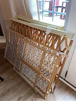 Five wood framed expandable child and animal safety gates stacked together. Various lattice and mesh patterns visible.