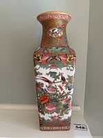 Front view of the vase showcasing colorful painted birds, flowers, and butterflies with a Greek key border at base and neck