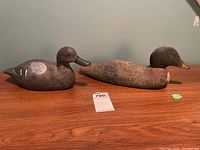 Photo of both carved duck decoys side by side on brown surface.
