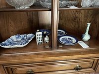 Old Foley square fluted plate with scenic design, two miniature ceramic houses, two Libertas plates, Broseley plate and Delft vase arranged inside a wooden display cabinet.