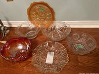 Photo showing the full set of glassware including amber platter, iridescent bowl, and four clear glass bowls with various cut patterns and sizes.