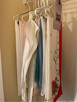 Side view of assorted table linens hanging on a rack showing various textures and colors including white, cream, and Christmas print.