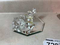 Photo showing three Swarovski figurines including a butterfly, swan, and small duck on a mirrored base.