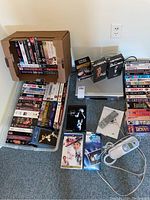 Photo showing a large collection of VHS tapes, the hard line telephone on the floor, and the VHS player partially visible.