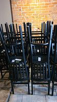 Multiple black metal bar stool frames stacked in a group, seats removed
