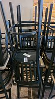 Photo depicting multiple black metal bar stools stacked showing the frame and seat back design.