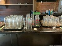 Three trays of mixed beer glasses on a bar surface including Coors, Guinness, and Molsons.