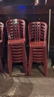 Photo showing stacks of red plastic chairs with vertical slat back design.