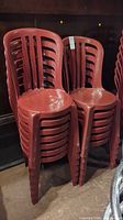 Photo of stacked red plastic chairs showing total count and general condition.