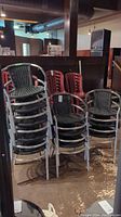 Stack of metal frame chairs with black plastic woven seats and backs shown from the front and side. Scrapes and scratches visible on metal frames.