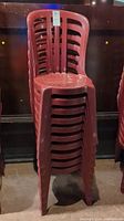 Stacked red plastic chairs showing their full height and overall shape.