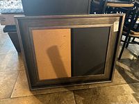 Front view of the framed dual board with corkboard on left and chalkboard on right.