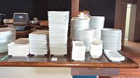 Overview of stacked rectangular plates of various sizes and shallow bowls on bar