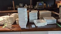 Stacks of small, medium and large white square plates on counter