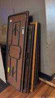 Stacked view of six folding tables against wall showing folded legs and tabletops