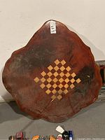 Frontal photo showing large wooden tree slab with painted chess/checker board in center, irregular edges, visible dark mold and surface scratches.