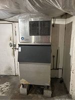 Front view of stainless steel ice maker on cinder blocks.