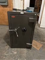 Front view of grey textured steel safe with three-spoke chrome handle and combination dial