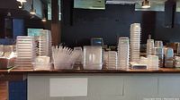 Wide view of multiple stacks of clear plastic trays and lids on counter