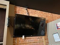 Haier 48 inch TV mounted on brick wall showing black bezel and screen.